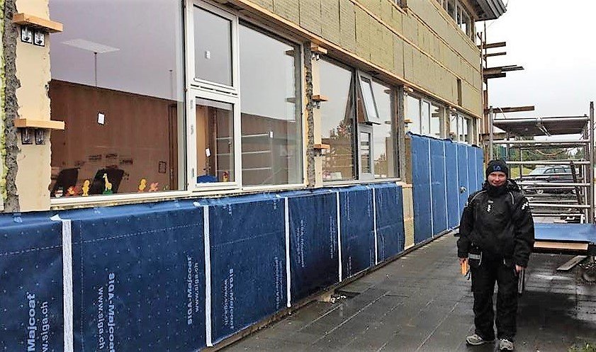 Starfsmaður að vinna að því að klæða skólann að utan.