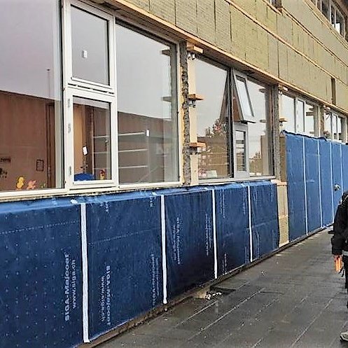 Starfsmaður að vinna að því að klæða skólann að utan.